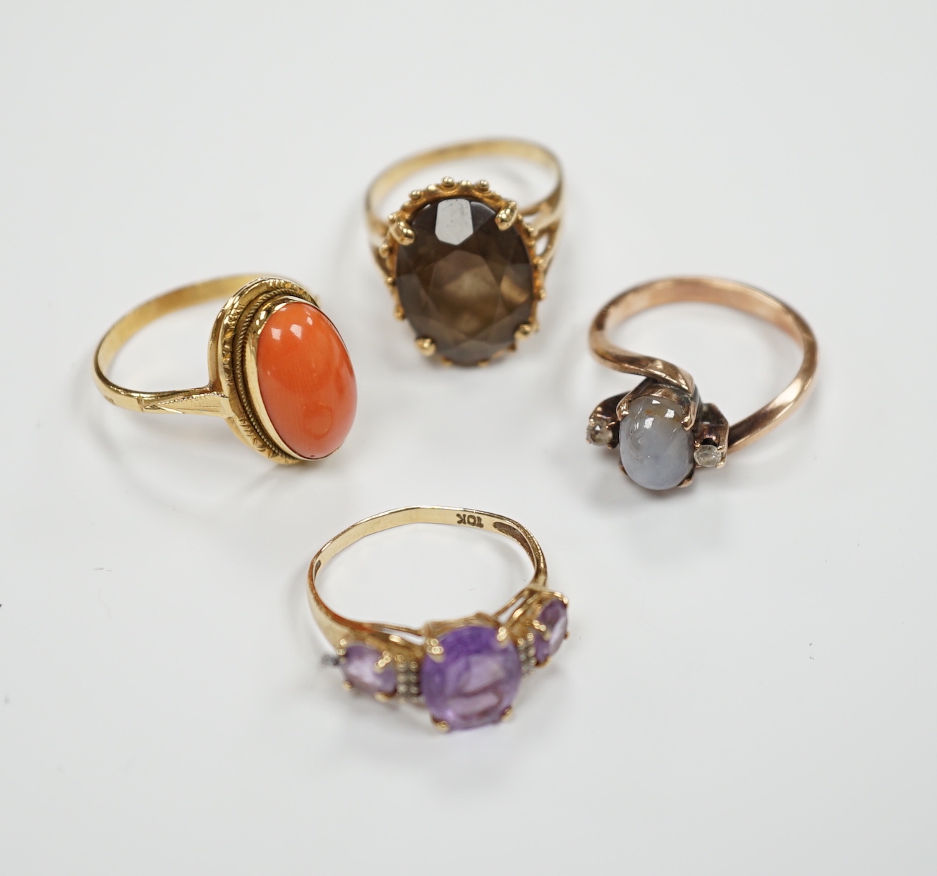 Two modern 10k and gem set rings, including amethyst and diamond chip and two yellow metal and gem set rings including coral set and star quartz? set, gross weight 15.9 grams.